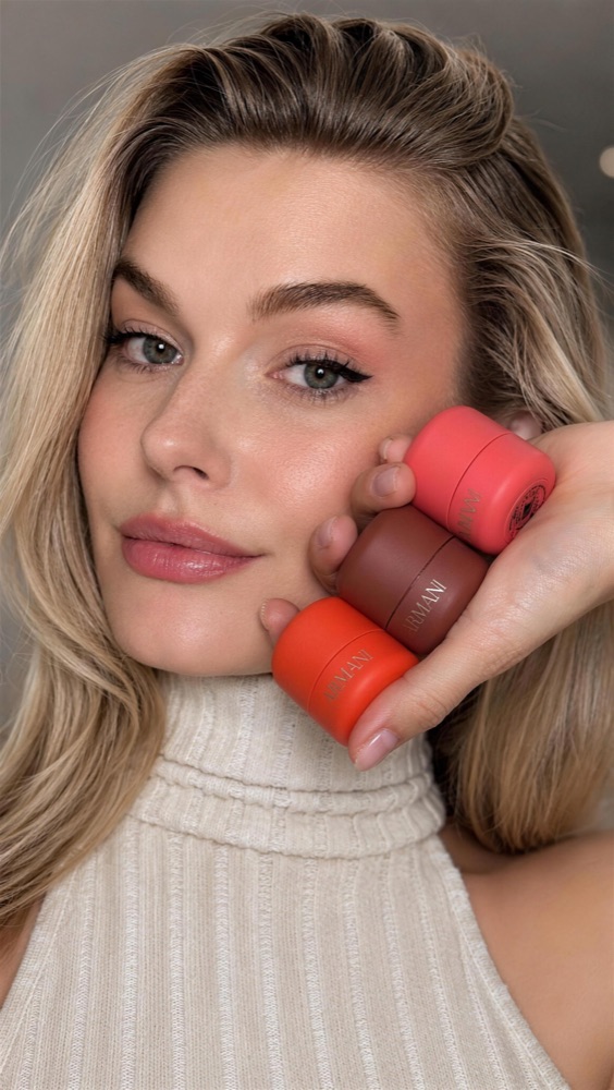 Alena holding three Armani beauty products against her cheek
