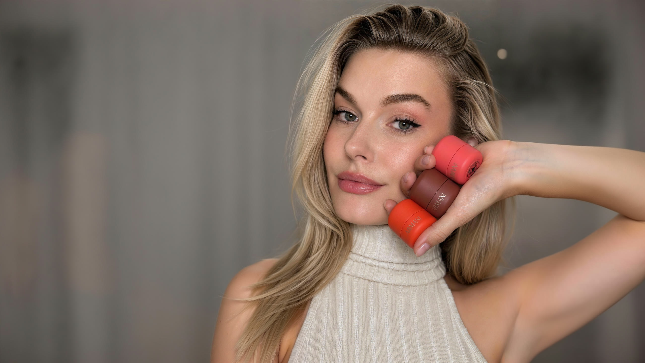 Alena holding three Armani beauty products against her cheek